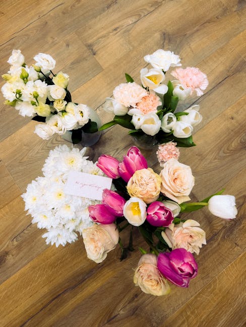 Three floral arrangements placed on a wooden surface, featuring a mix of fresh flowers. The first bouquet, positioned at the top, contains small white roses, green buds, and delicate white filler flow