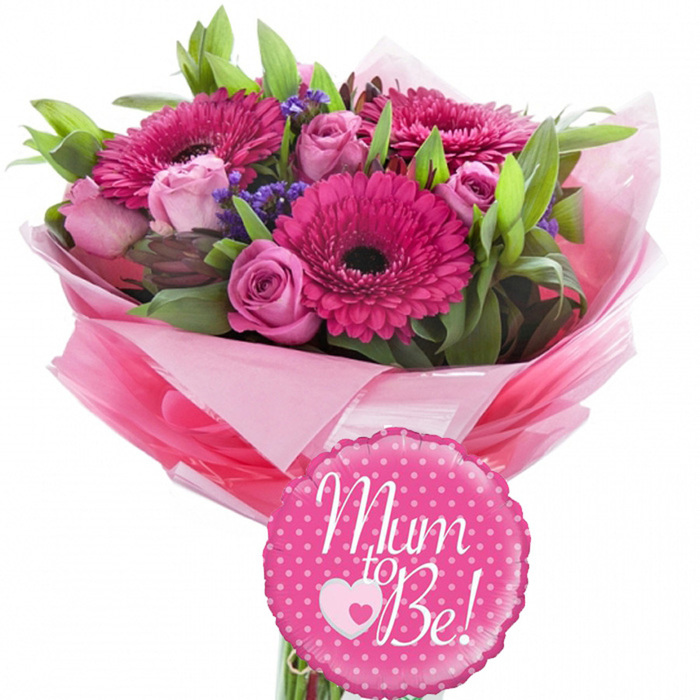 A charming maternity-themed bouquet with a coordinated balloon is shown against a pure white background, creating a fresh, uncluttered stage for the uplifting colours, much like the calm light filtering into a Yiewsley home on a special day. The bouquet features several large gerbera daisies in a vivid shade of fuchsia pink, each flower head perfectly formed with smooth petals arranged in tight, circular layers around dark, almost black centres that anchor the design visually. Between these dynamic blooms, soft pink roses weave in and out, some still in compact buds, others more open, revealing concentric rings of velvety petals that add a sense of softness and romance. Threaded throughout are fine, slightly cloud-like clusters of small purple filler flowers, offering delicate texture and gentle contrast to the richer pink shades. A generous selection of green foliage surrounds and supports the blooms, combining slender, pointed leaves with broader, glossier ones to build volume and give the bouquet its rounded, balanced silhouette. The stems are wrapped neatly in layers of pink tissue and transparent cellophane, the wraps folded into loose, ruffled edges that flare out like a skirt, enhancing the overall celebratory feel. In front of the base, slightly overlapping the stems, stands a round, scalloped-edge foil balloon in bright pink, decorated with crisp white polka dots. Across its centre, the message Mum to Be! is written in smooth, white script that curves gently with the balloon's shape. A small design beneath the text shows a tiny pink heart enclosed within a larger white heart outline, underscoring the tenderness of the occasion. This image embodies joy, anticipation, and affection, the sort of gift you might send for a baby shower near Stockley Park or to congratulate a Yiewsley neighbour on their pregnancy.