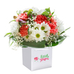 Joyful and inviting, this bouquet gathers the spirit of Yiewsley into one exquisite arrangement. Plump coral carnations open with gentle, ruffled edges, their warm tones balanced beautifully by snowy white daisies that centre each cluster with a lively burst of fresh yellow-green. Throughout, sprigs of baby's breath float like tiny, whimsical clouds, bringing softness and air to the vibrant bouquet. Shiny, deep green foliage sweeps gracefully around the edge, cradling each bloom as if inspired by the greenery found in local Yiewsley parks. On the left, a few purple-tipped buds peek from behind, lending a quiet sense of hope and elegance. The bouquet is carefully set upright in a sleek white square bag with sturdy ribbon handles-perfect for gifting or surprising someone special in Yiewsley on their birthday, for an anniversary, or to illuminate a loved one's day. Set against a flawless white backdrop, the flowers' freshness and the artistry of local floristry are unmistakable, making this arrangement a luminous celebration of thoughtfulness, nature, and heartfelt intention.